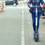 Young happy woman riding an electric scooter in the city