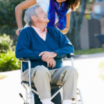 Adult Daughter pushing her father in a wheelchair outdoors