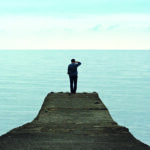 Man standing on the edge of the pier on the sea background