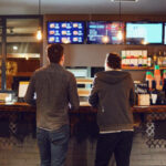 Rear view. Two men choose food in a fast food restaurant. Bar snack concept .