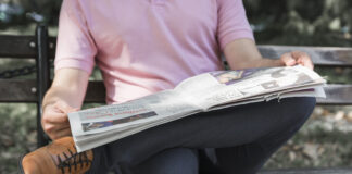 Homme qui lis son journal assis sur un banc