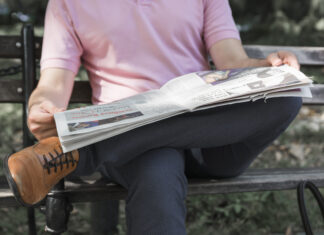 Homme qui lis son journal assis sur un banc