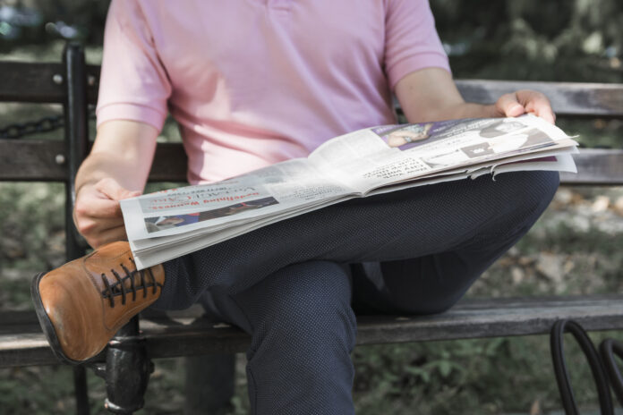 Homme qui lis son journal assis sur un banc