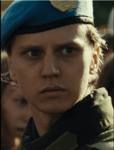 Un soldat en uniforme militaire avec un béret bleu et un insigne doré.
