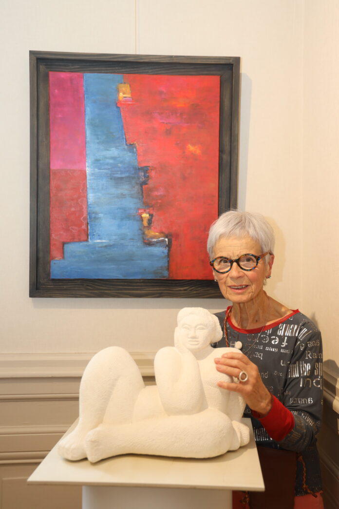 Femme artiste devant sa sculpture et son tableau