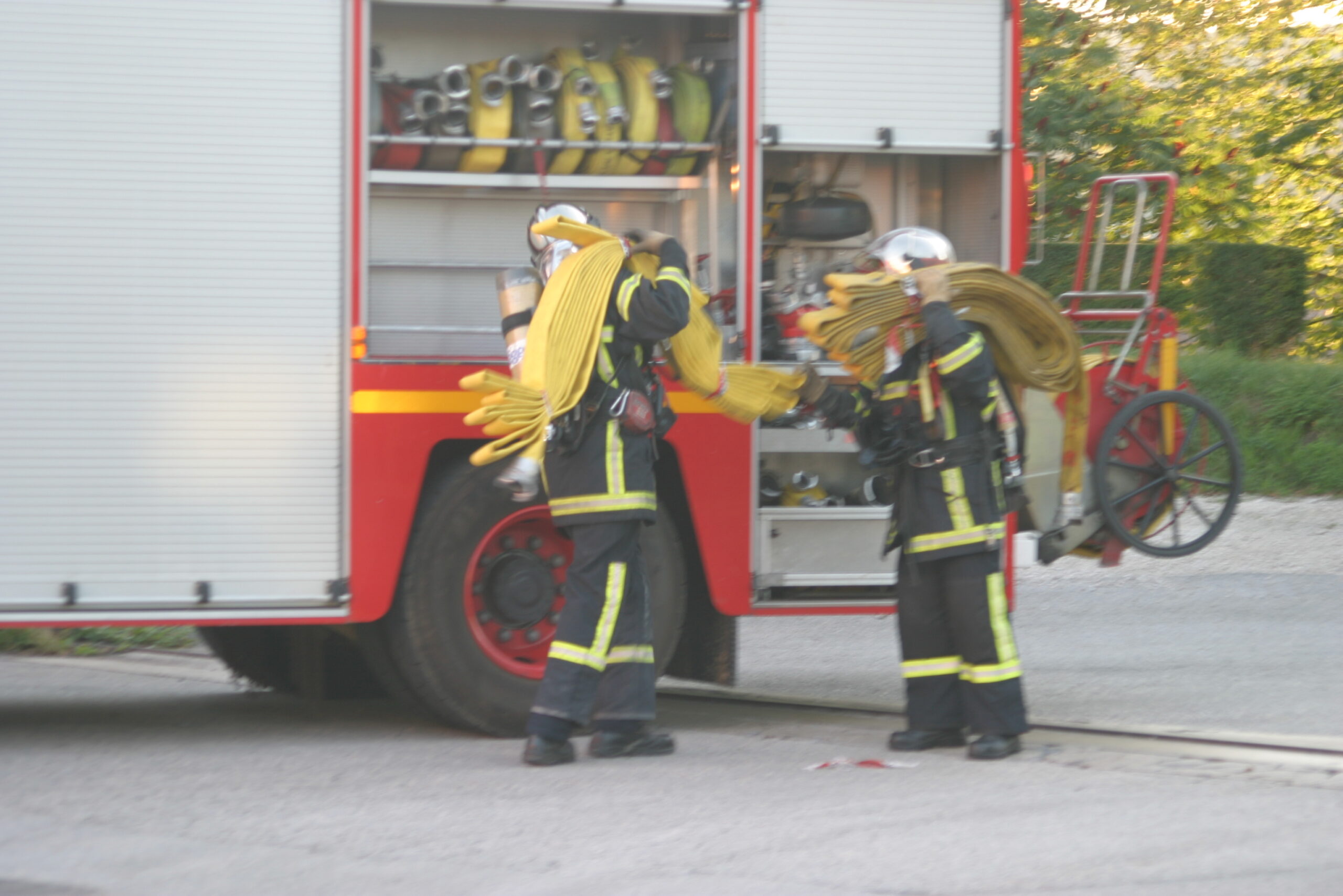 Pompiers avec une lance incendie sur les épaules