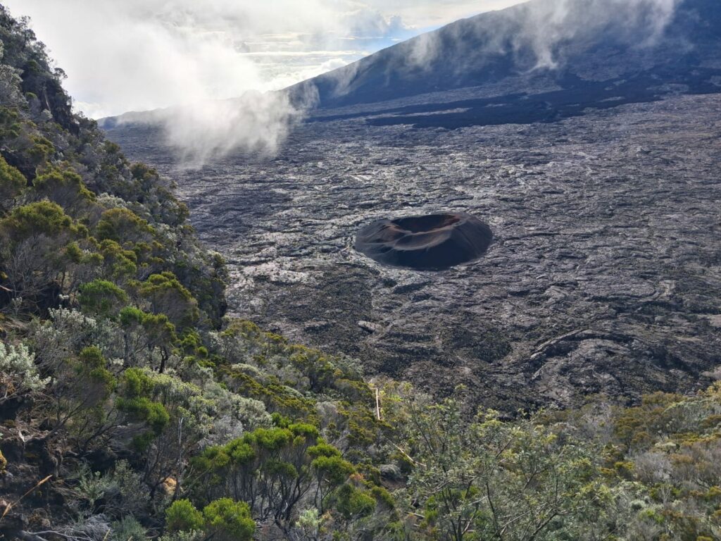 Vue aérienne du cratère du Piton de la Fournaise entouré de paysage volcanique.