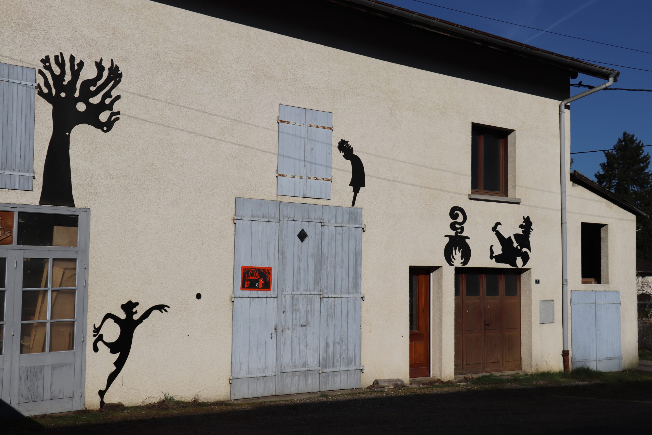 Façades du village artistique décorées de silhouettes noires découpées.