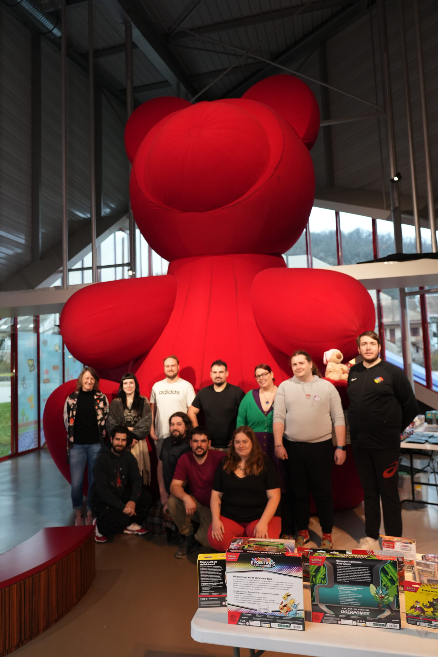 Groupe de personnes devant un grand ours rouge au musée du jouet, lors d