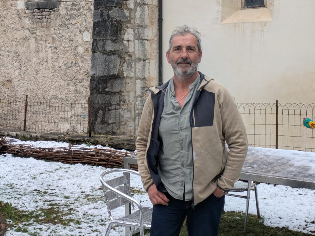 Homme debout devant un bâtiment en hiver, lié aux baignades froides au lac Genin.