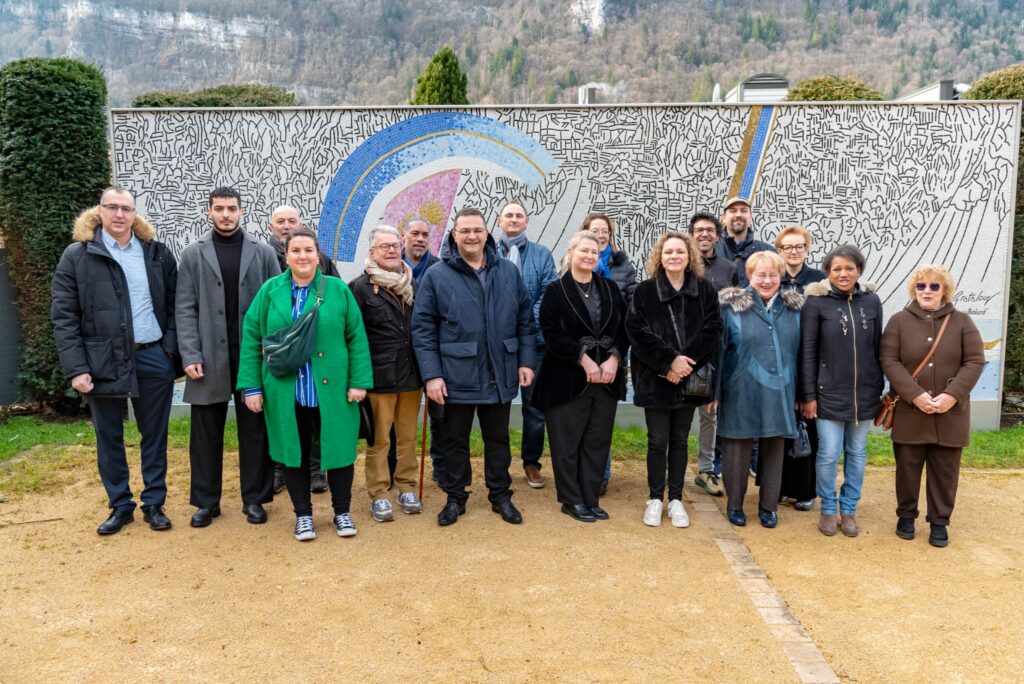 Groupe de personnes devant un panneau mural coloré à Nantua, lors des municipales pour une ville autonome financièrement.
