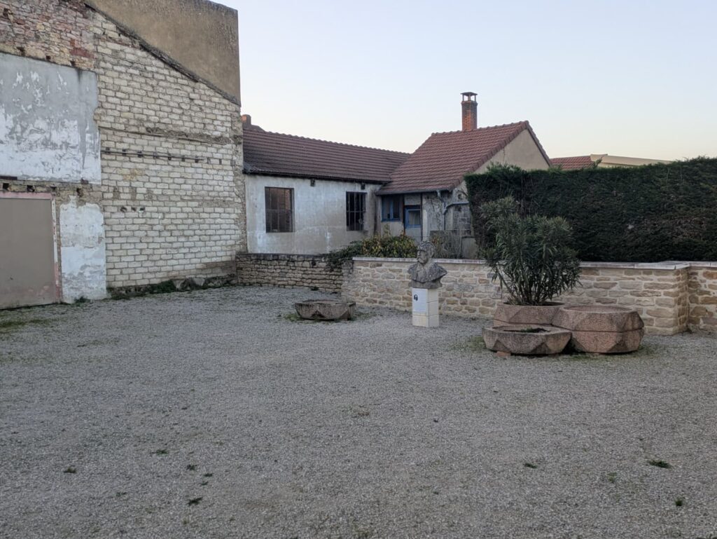 Cour extérieure avec statue devant un bâtiment en travaux à Louhans, prévue pour rénovation muséale liée à la sécurité.