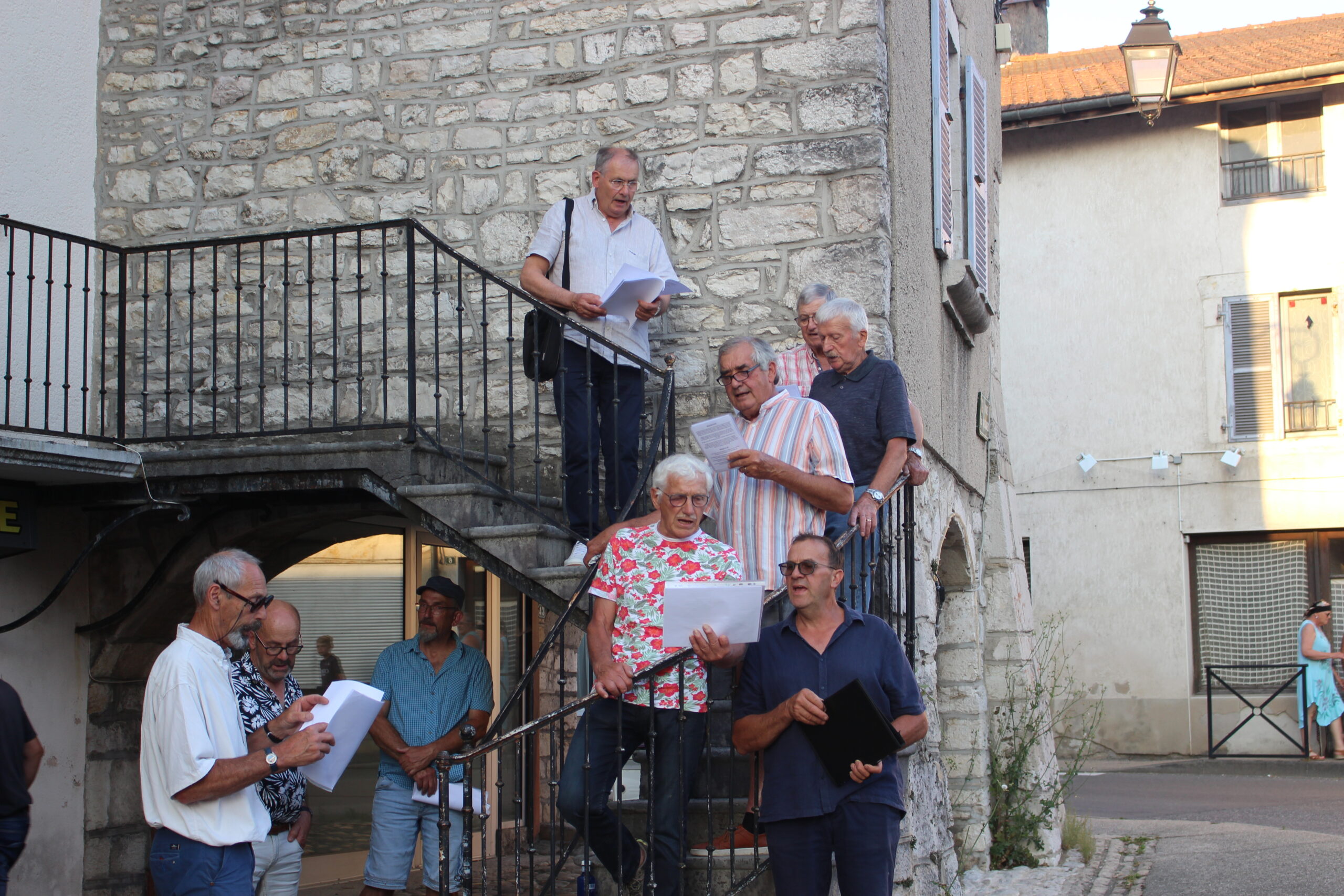 Groupe de chanteurs répétant sur un escalier extérieur en pierre.