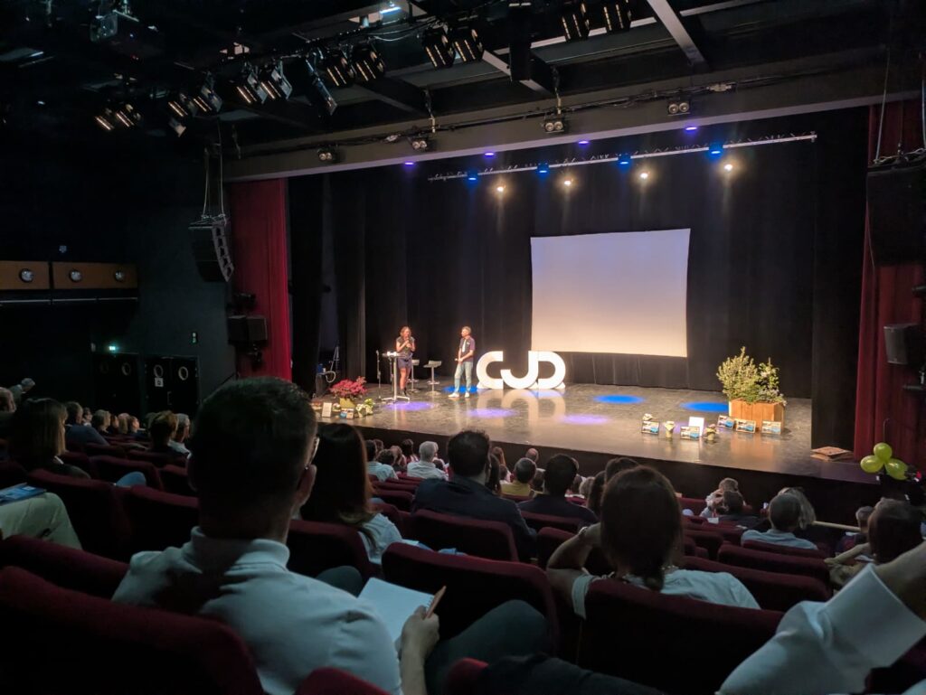 Conférence avec public assis écoutant un intervenant