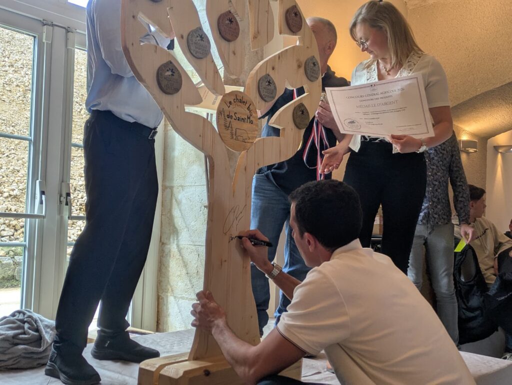 Quentin Fillon-Maillet signant une dédicace sur arbre de médailles