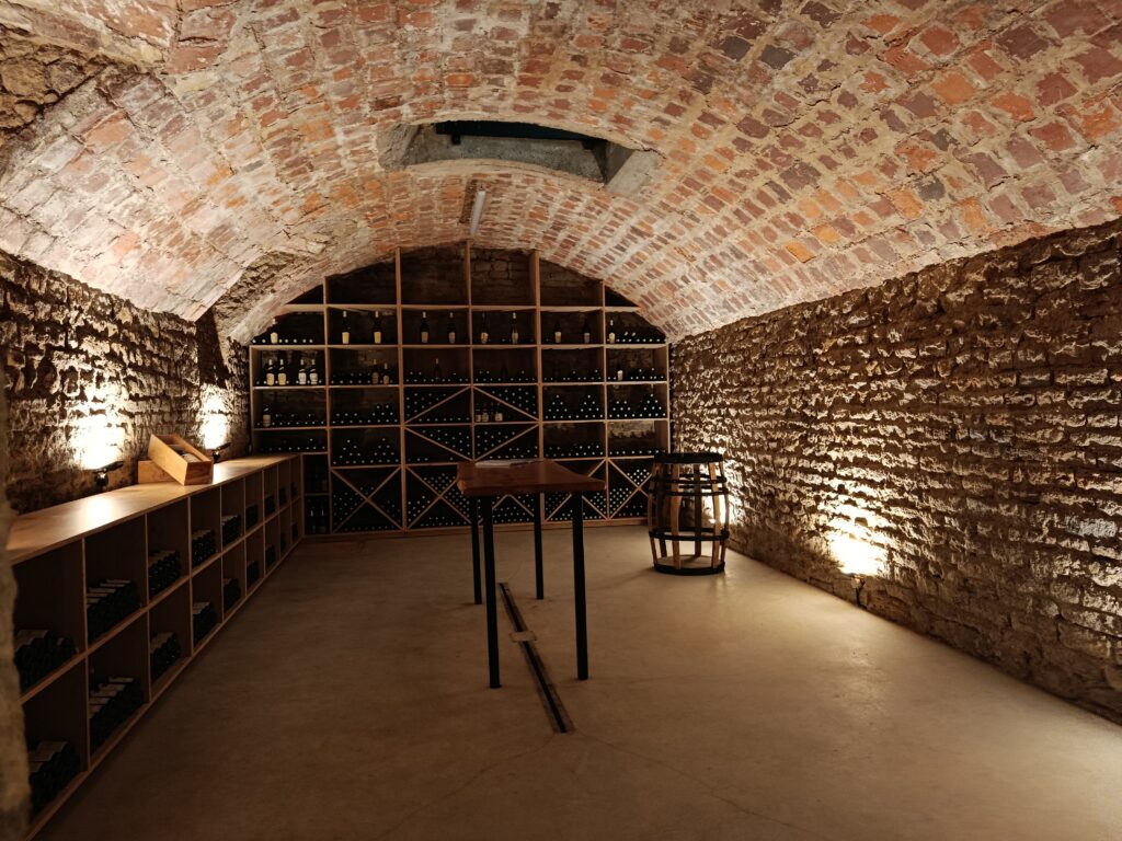 Cave voûtée de l’œnothèque, bouteilles et barriques