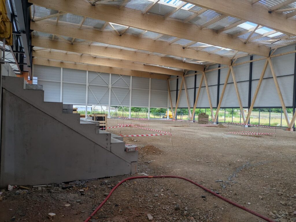 Grande salle sportive en chantier, structure bois et tribunes