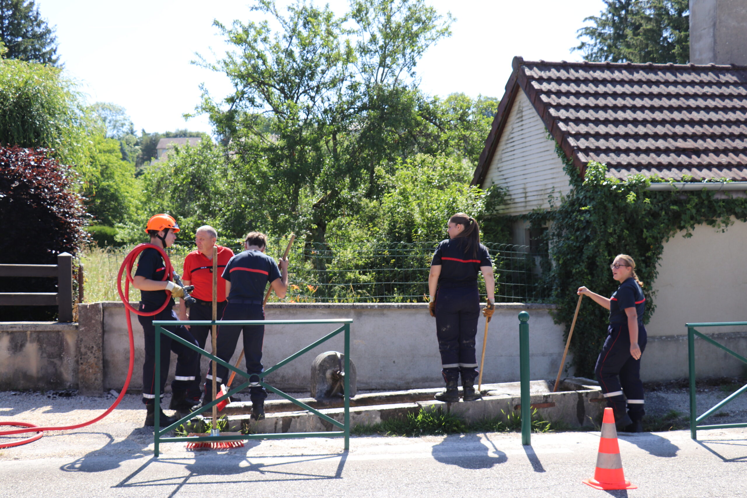 Jeunes sapeurs-pompiers nettoyant une fontaine à Arinthod